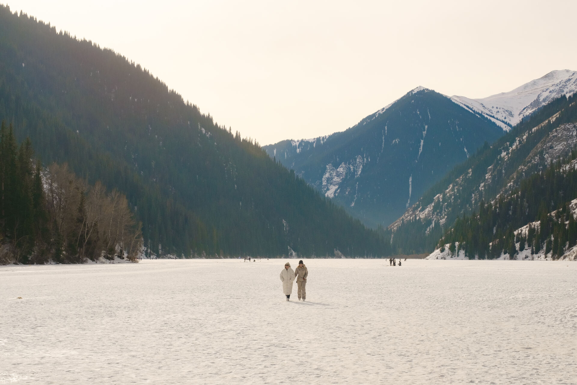 Two people walking on frozen Kolsai Lake